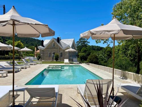 a swimming pool with chairs and umbrellas in front of a house at Villa Boutique 1880-Romantic Historic Boutique Hotel with Outdoor Jacuzzi in San Salvador