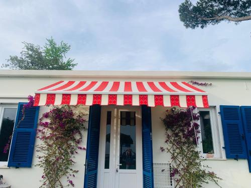 a white house with a red awning and blue shutters at La Casetta di Dante in Marina di Carrara
