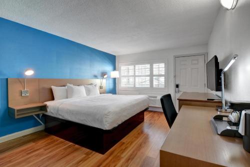 a bedroom with a bed and a desk with a television at Signature Inn Medford Downtown - Newly Renovated in Medford