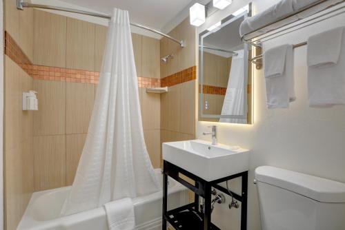 a bathroom with a sink and a toilet and a tub at Signature Inn Medford Downtown - Newly Renovated in Medford