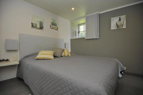 a bedroom with a bed with a yellow pillow on it at Le Clos Sigebert in Libramont