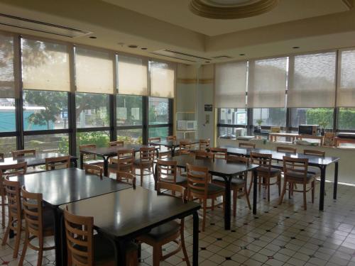 - une salle à manger avec des tables, des chaises et des fenêtres dans l'établissement Hotel Tsukuba Hills Umezono, à Tsukuba