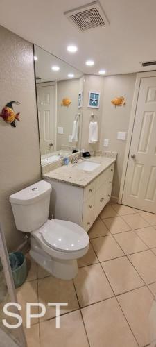 a bathroom with a toilet and a sink and a mirror at Fiesta Sol #110 in South Padre Island