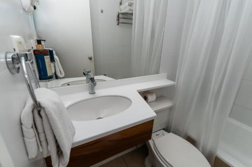 a white bathroom with a sink and a toilet at Hotel Don Luis Puerto Montt in Puerto Montt
