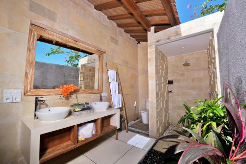 Un baño con dos lavabos y una ducha. en The Tamantis Villa, en Canggu
