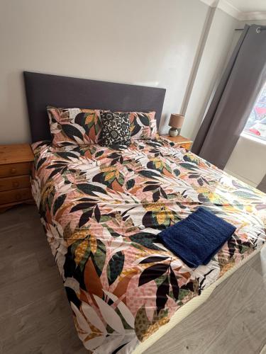 a bed with a colorful comforter and two pillows at Bel City in Thornton Heath