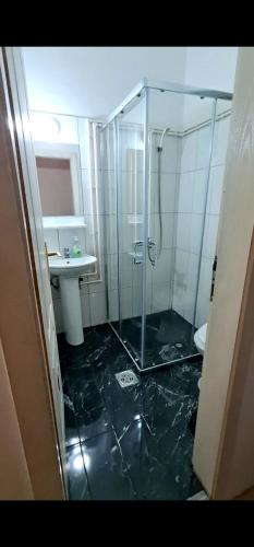 a bathroom with a glass shower and a sink at Hostel Paparazzo & Apartmans in Kikinda