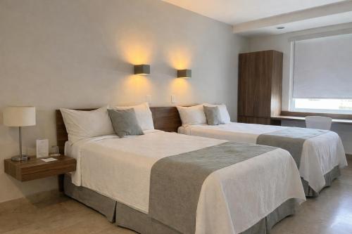a hotel room with two beds and a window at One Villahermosa 2000 in Villahermosa