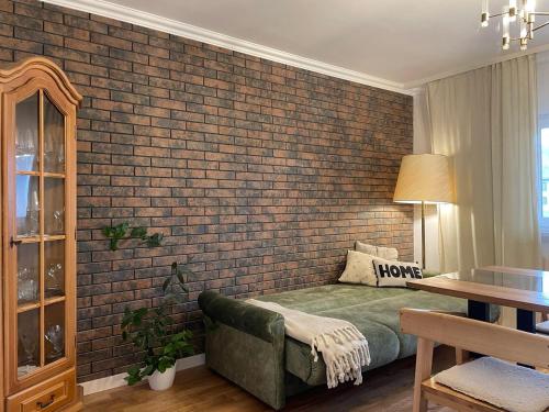a bedroom with a brick wall and a green couch at Pstrug House in Yasinya