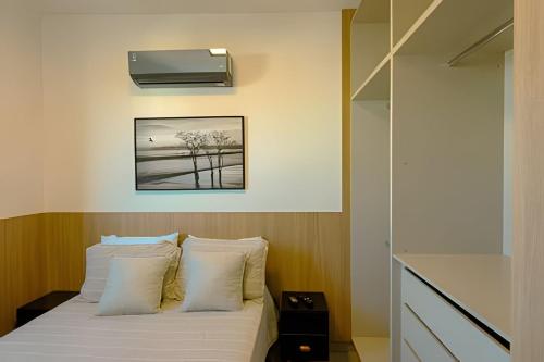 a bedroom with a white bed with a tv on the wall at Studios ZP in Uberlândia