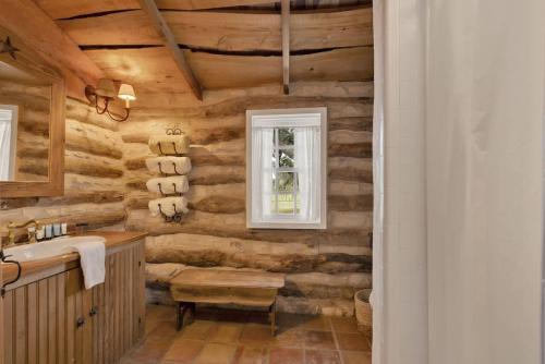 a bathroom with wooden walls and a sink and a window at 7Cs Sunset Valley Ranch in Fredericksburg