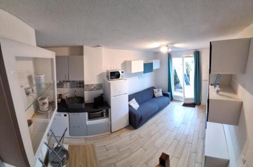 a small kitchen and living room with a blue couch at Villa Club T2 complètement rénové à Mar Vivo, plages à pieds, piscine in La Seyne-sur-Mer