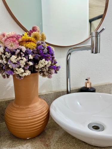 a vase with flowers on a counter next to a sink at EcoStay Lençóis - apartamento in Lençóis