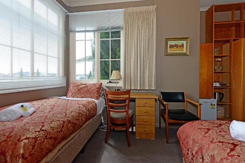 1 dormitorio con cama, escritorio y ventana en Edinburgh Gallery Bed & Breakfast, en Hobart