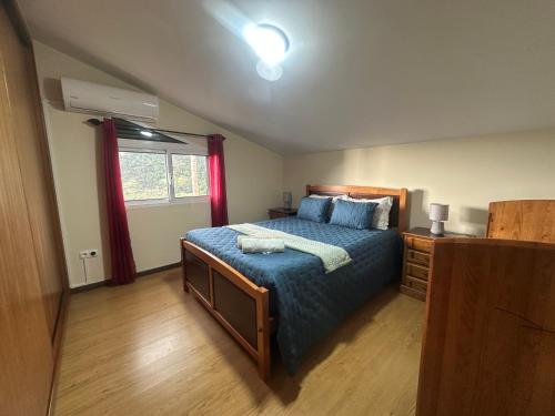a bedroom with a bed with a blue comforter and a window at The House of Passos in Ponta do Sol