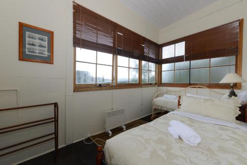 a bedroom with a bed with white sheets and windows at Edinburgh Gallery Bed & Breakfast in Hobart