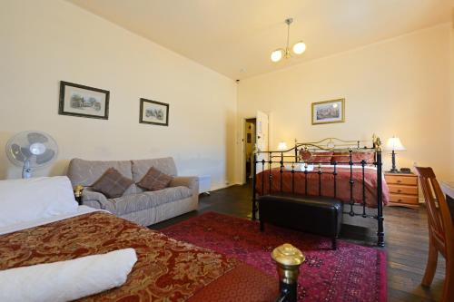 a bedroom with a bed and a couch and a bed and a living room at Edinburgh Gallery Bed & Breakfast in Hobart