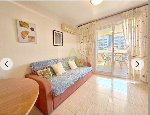 a living room with a couch and a balcony at Beachfront apartment in Oropesa del Mar