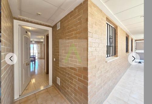 a room with a brick wall and a hallway at Beachfront apartment in Oropesa del Mar