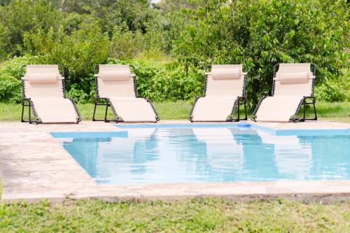 eine Gruppe von Gartenstühlen und ein Swimmingpool in der Unterkunft Finca La Vertiente in El Encón