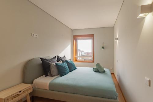 a small bedroom with a bed with blue pillows at 3D Apartamento a 3 minutos da praia in Matosinhos