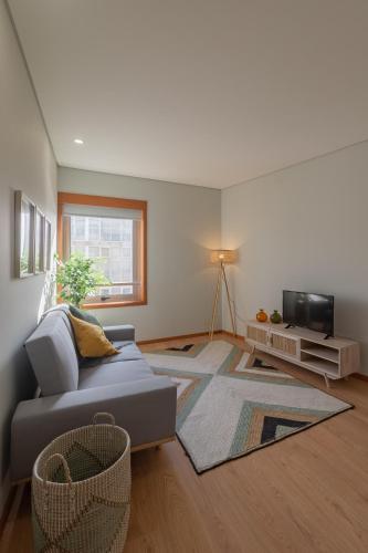 a living room with a couch and a tv at 3D Apartamento a 3 minutos da praia in Matosinhos
