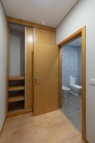a bathroom with a toilet and a wooden door at 3D Apartamento a 3 minutos da praia in Matosinhos