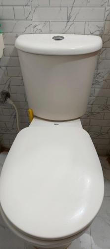 a white toilet in a bathroom with a wall at Park Amaira Banani Guesthouse in Dhaka