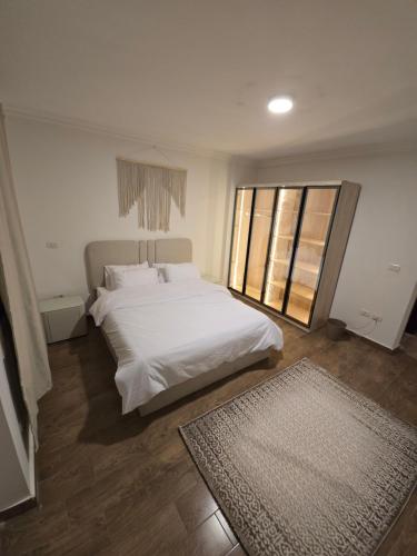 a bedroom with a white bed and a large window at Modern 3BR Apartment - Heart of Sheikh Zayed - Gated Compound in Sheikh Zayed