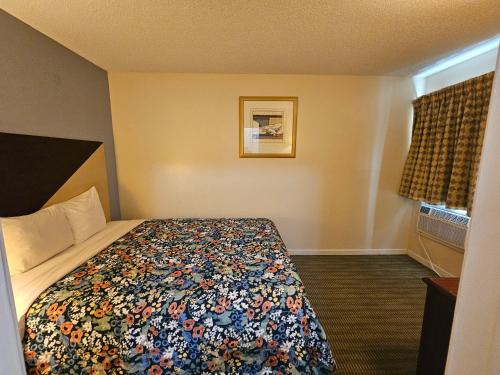 a hotel room with a bed with a colorful blanket at Merrimac Inn and Suite in Williamsburg