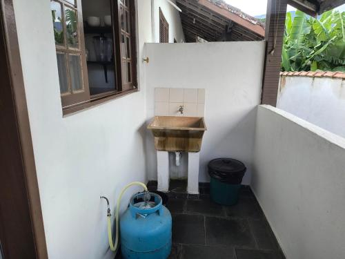 a bathroom with a sink and a bucket at Pousada e Chalés Santorini in Caraguatatuba