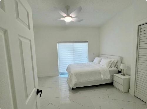 a white bedroom with a bed and a ceiling fan at Beautiful House Near Marlins Stadium in Miami