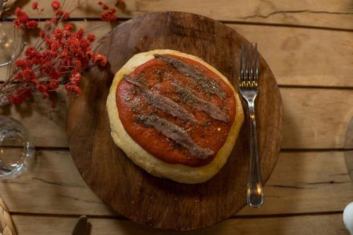 a wooden plate with a pizza on a table with a fork at Le Conche country house in Villamaina