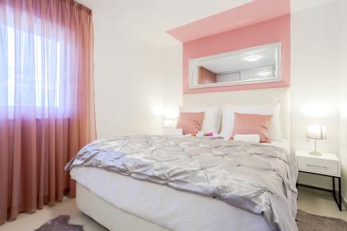 a bedroom with a large bed with pink walls at Exclusive Apartment MARIJA in Strožanac