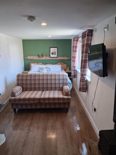 ein Schlafzimmer mit Bett, Sofa und Fernseher in der Unterkunft Wee Shot in Tain
