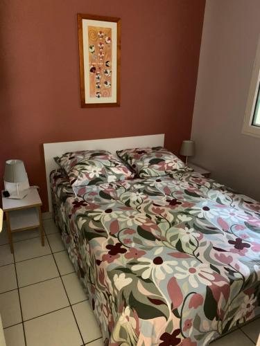 a bedroom with a bed with a floral comforter at L escale Oceane in Moliets-et-Maa