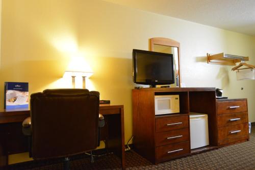 a hotel room with a desk with a television and a chair at Baymont by Wyndham Kasson Rochester Area in Kasson