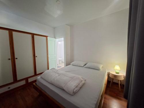 a white bedroom with a bed and a table at Bungalow Miti in Uturoa