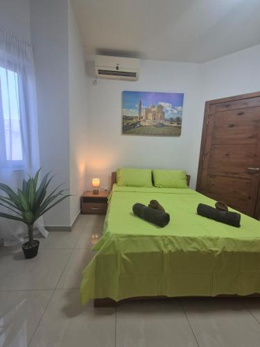 a bedroom with a green bed and a painting on the wall at Central 1 BR Retreat in Il-Gżira