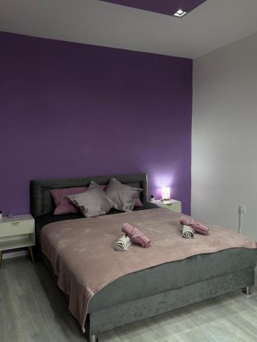 a bedroom with a large bed with purple walls at Apartman LILLY in Paraćin