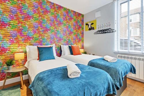 two beds in a room with a colorful wall at Rainbow Studio By My Getaways in Brighton & Hove