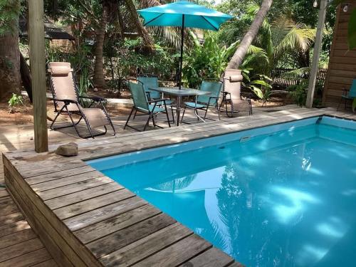 a pool with a table and chairs and an umbrella at Jonathans Cabins in Utila