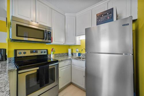 a kitchen with white cabinets and a stainless steel refrigerator at Beach, Please! Oceanfront, Balcony & Sunrise Views in North Topsail Beach