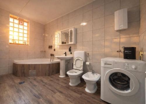 a bathroom with a toilet and a tub and a washing machine at Pura Vida Apartment in Mostar