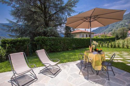 a table and chairs with a table and an umbrella at Lenno Dolcelago in Lenno