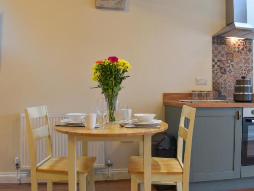 a table with a vase of flowers on it in a kitchen at The Loft - Uk50284 in Earl Sterndale