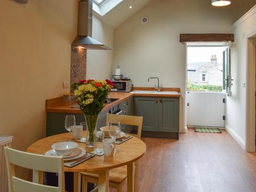 a kitchen with a table with a vase of flowers on it at The Loft - Uk50284 in Earl Sterndale