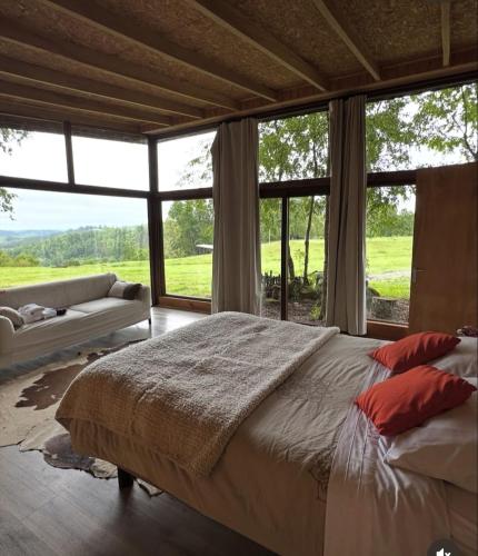 a bedroom with a large bed and large windows at Samadhi Eco Resort in Vilcún