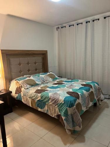 a bedroom with a bed with a comforter and curtains at Cuarto cómodo y económico cerca Expo GDL Plaza Sol in Guadalajara