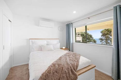 a bedroom with a bed and a large window at Beachfront Studio - Ocean Views - Bell Block in New Plymouth